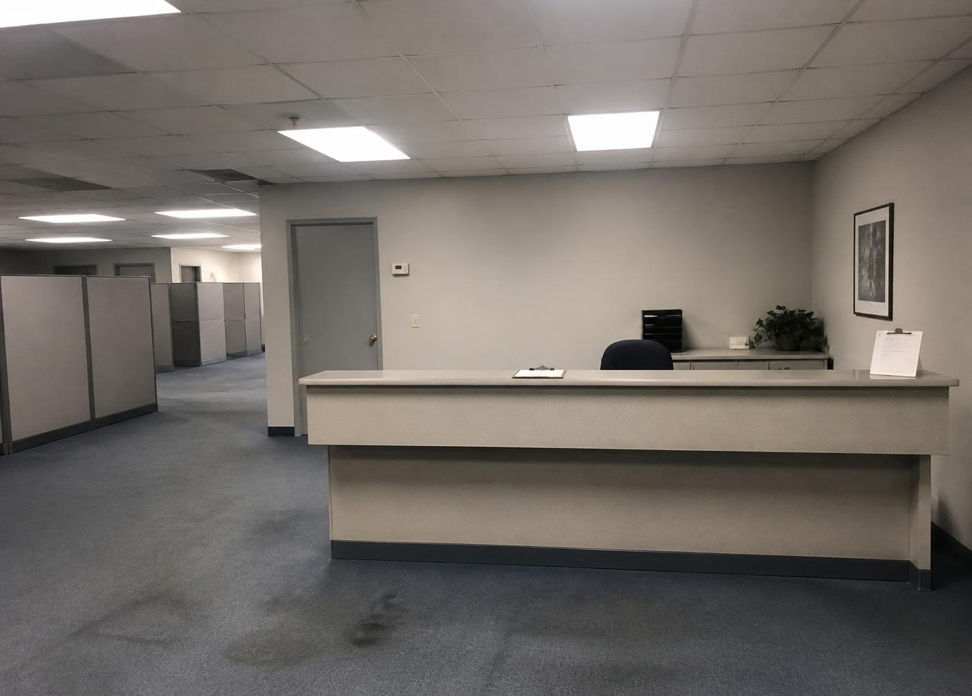 Office reception before redesign with gray cubicles and fluorescent lighting